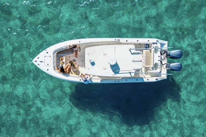 Aerial view of a white boat with people on turquoise water.