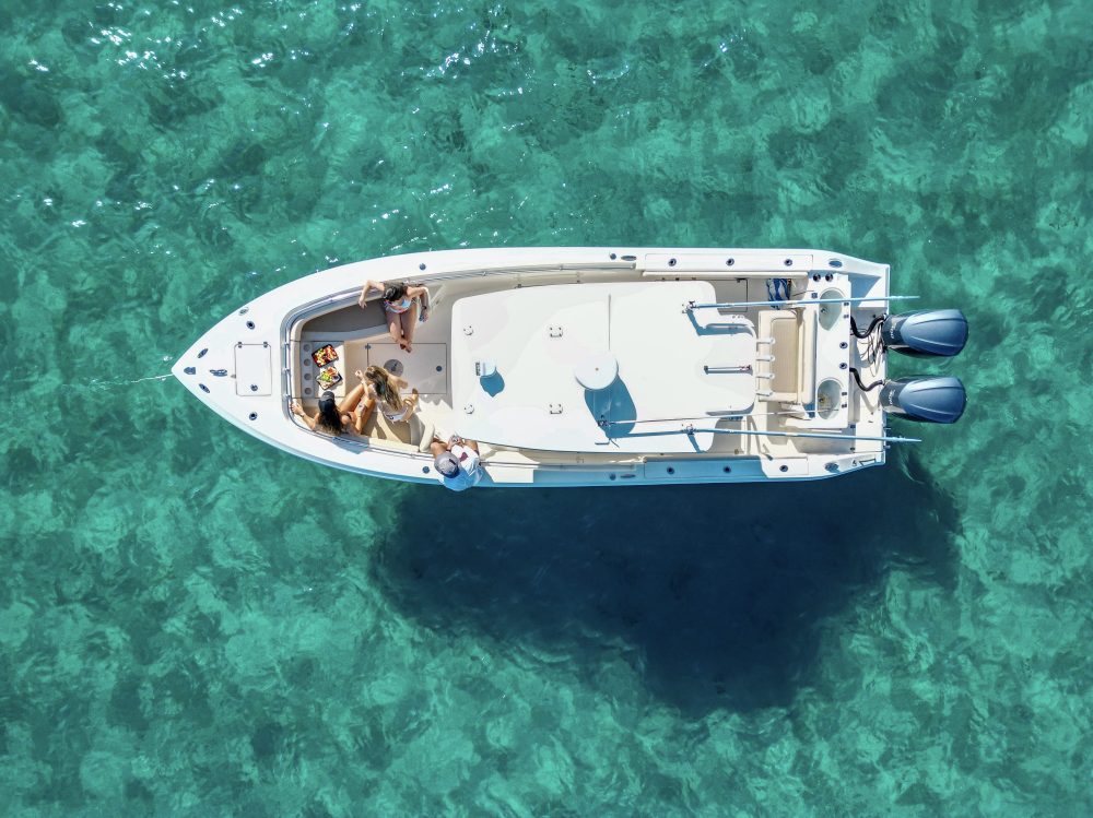 Aerial view of a white boat with people on turquoise water.