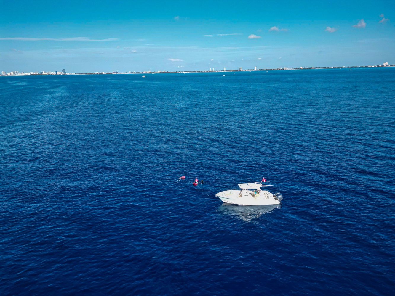 Small boat floating on a vast blue ocean under a clear sky.