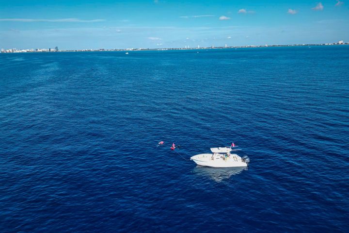 Small boat floating on a vast blue ocean under a clear sky.
