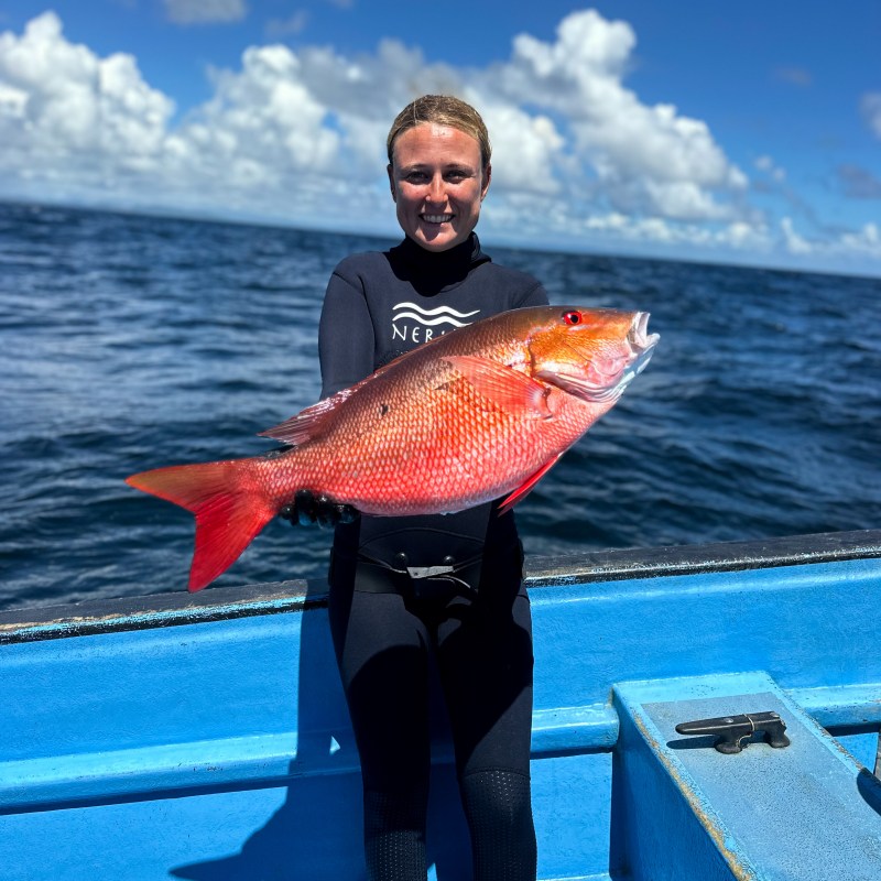 a man holding a fish in front of a body of water