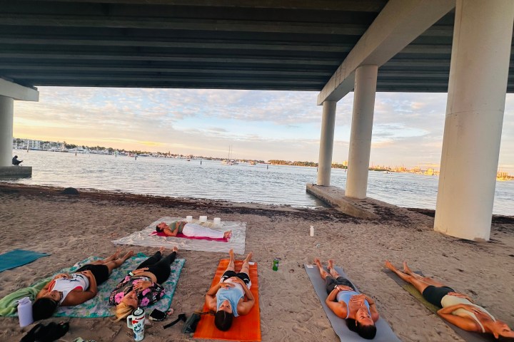 People doing yoga on the beach