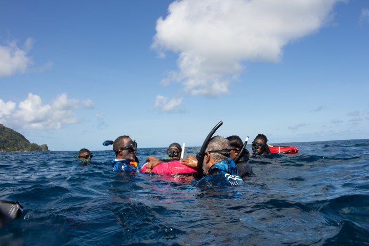 Group of snorkelers floating in the ocean under a clear sky.